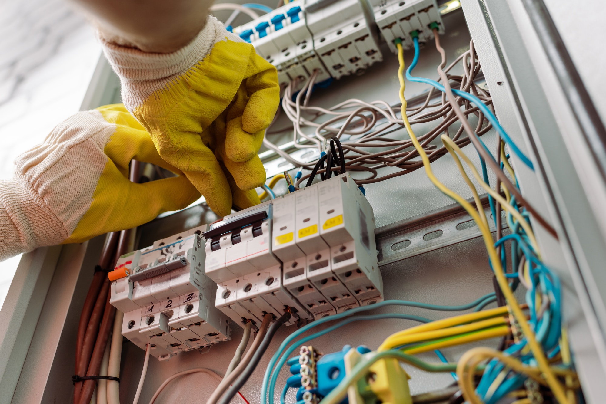 Low angle view of electrician in gloves fixing electrical distribution box